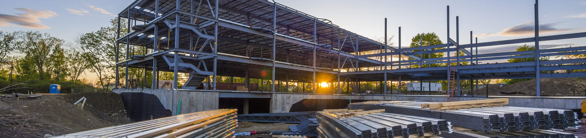 Construction site with steel flooring in front of a  partially erected building at sunset